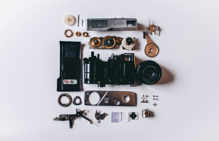 Flat lay of various disassembled camera parts on a white surface showcasing intricate details.