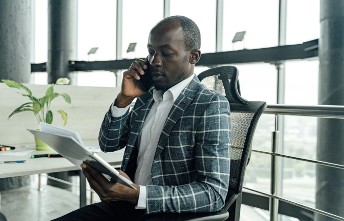Professional businessman discussing documents during a phone call in a modern office setting.