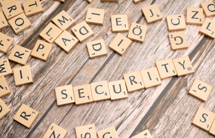 Wooden letter tiles form the word 'Security' amidst scattered tiles on wood.