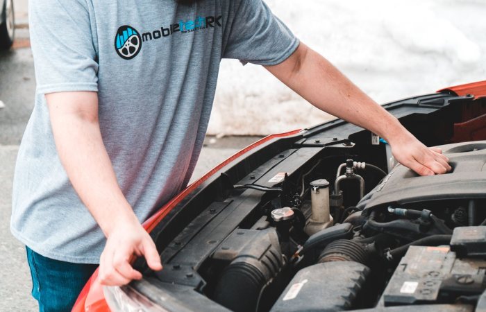 A man inspects the engine of a car, likely addressing an emergency breakdown.